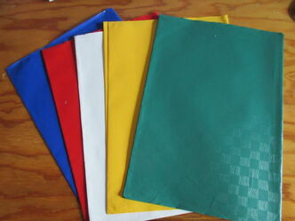 ein blauer, ein roter, ein weißer, ein gelber und ein grüner Umschlag liegen auf einem braunen Tisch