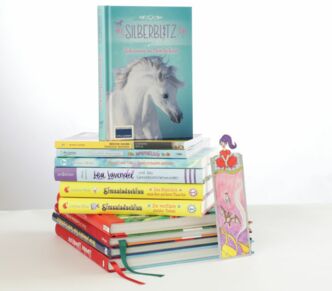 Stapel von Kinderbüchern der Autorin Corinna Wieja, ganz oben "Silberblitz", daneben ein Lesezeichen zur Buchreihe "Simsaladschinn"