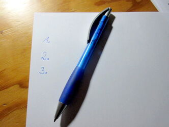 Auf einem Blatt Papier mit den Zahlen 1., 2. und 3. liegt ein blauer Kuli.