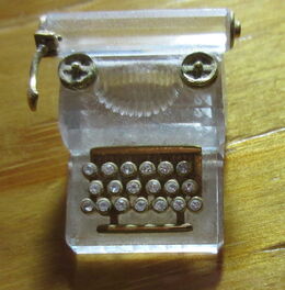 Kleine gläserne Schreibmaschine auf Holztisch